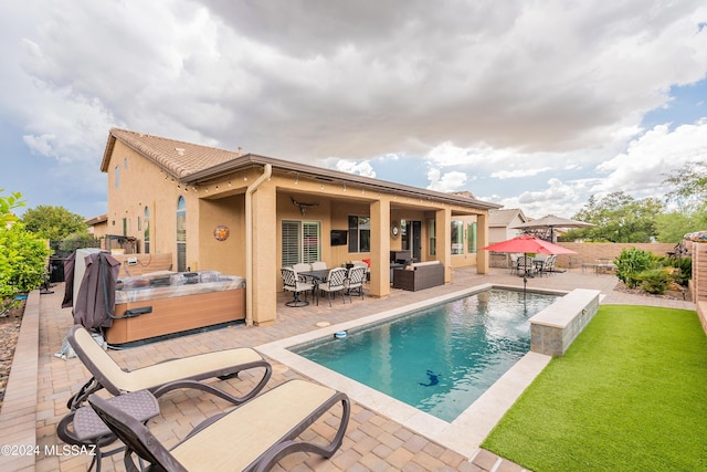 rear view of house with a swimming pool with hot tub, an outdoor hangout area, and a patio