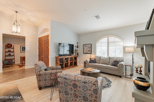 living room featuring light wood-type flooring, lofted ceiling, and an inviting chandelier