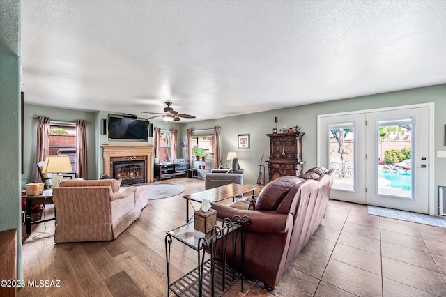 living room with a textured ceiling, ceiling fan, and hardwood / wood-style floors