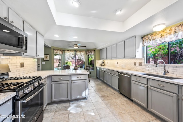 kitchen featuring backsplash, stainless steel appliances, kitchen peninsula, sink, and a raised ceiling