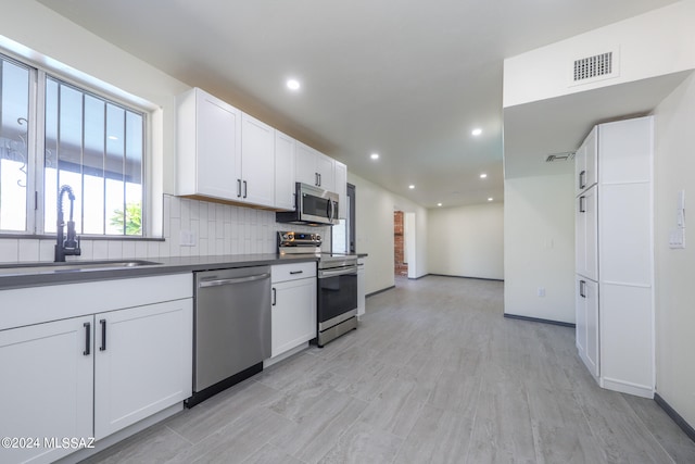 kitchen featuring light wood-type flooring, white cabinets, stainless steel appliances, and sink