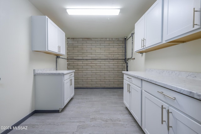 kitchen featuring brick wall and white cabinets