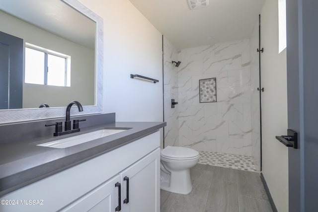 bathroom featuring tiled shower, toilet, hardwood / wood-style flooring, and vanity