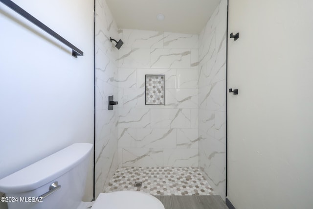 bathroom featuring tiled shower and toilet