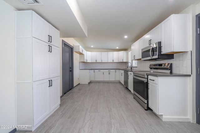 kitchen featuring white cabinets, light hardwood / wood-style flooring, stainless steel appliances, sink, and decorative backsplash