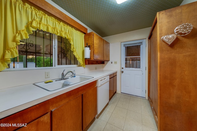 kitchen featuring white dishwasher, light tile patterned floors, and sink