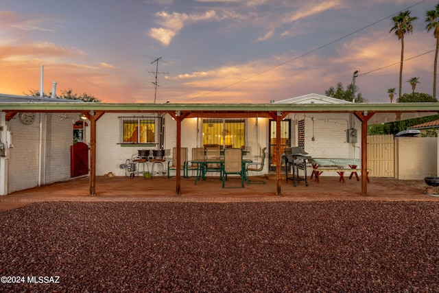 back house at dusk featuring a patio