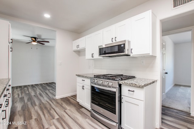 kitchen with white cabinets, light wood-type flooring, light stone countertops, stainless steel appliances, and ceiling fan