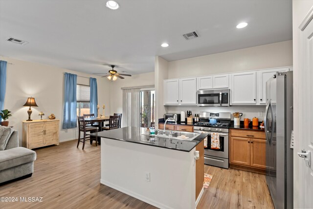 kitchen featuring light hardwood / wood-style flooring, an island with sink, stainless steel appliances, white cabinetry, and ceiling fan