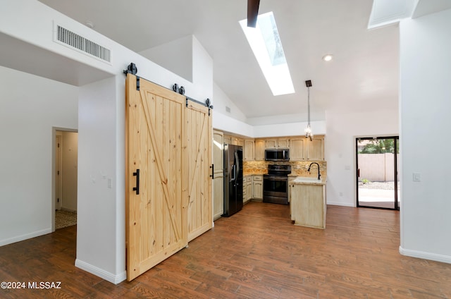 kitchen with dark hardwood / wood-style flooring, light brown cabinets, appliances with stainless steel finishes, and a barn door