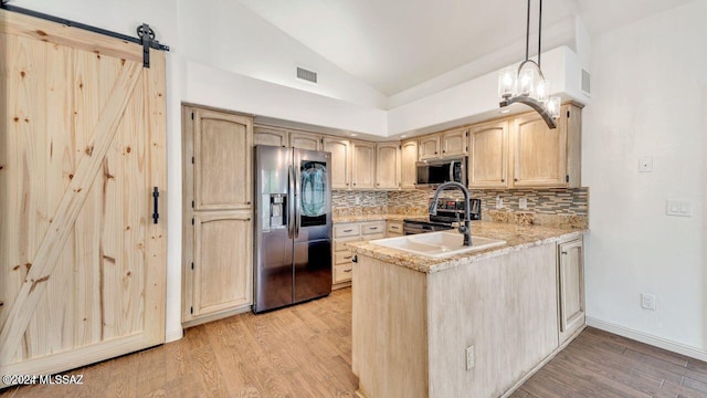 kitchen with appliances with stainless steel finishes, hanging light fixtures, light hardwood / wood-style floors, decorative backsplash, and light brown cabinetry