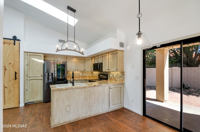 kitchen featuring dark wood-type flooring, hanging light fixtures, a barn door, stainless steel appliances, and light brown cabinets