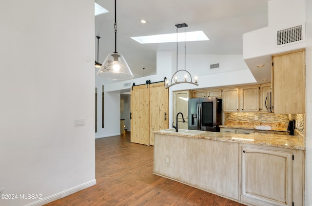 kitchen with sink, hanging light fixtures, a barn door, light brown cabinets, and appliances with stainless steel finishes