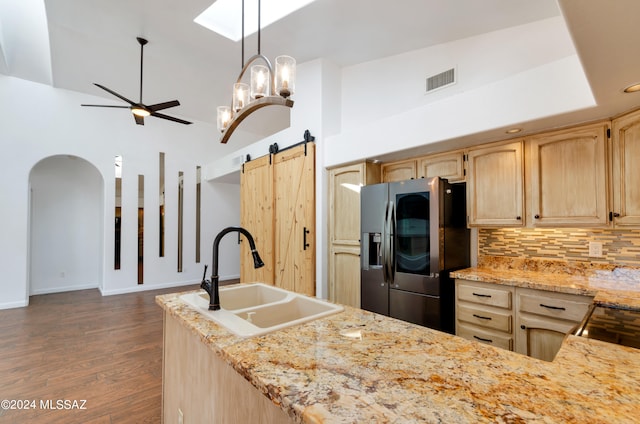 kitchen featuring a barn door, stainless steel fridge, sink, and high vaulted ceiling