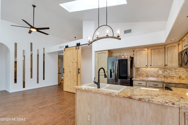 kitchen featuring stainless steel fridge, hanging light fixtures, a barn door, dark hardwood / wood-style floors, and sink