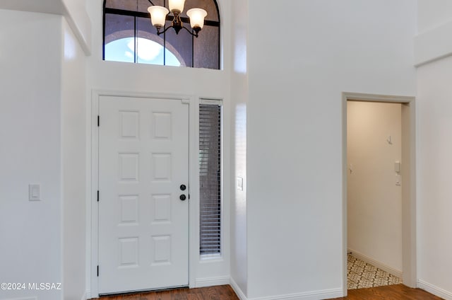 entryway featuring an inviting chandelier, a towering ceiling, and hardwood / wood-style floors