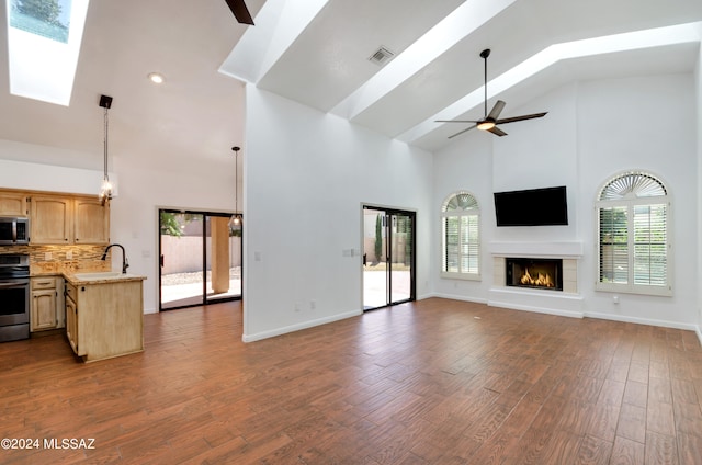 unfurnished living room with a healthy amount of sunlight, dark hardwood / wood-style floors, and high vaulted ceiling