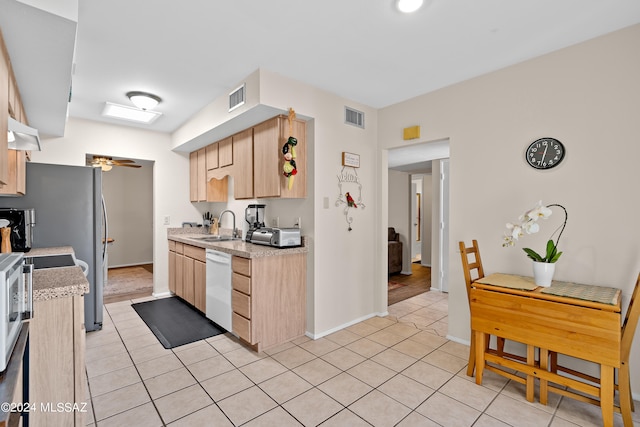 kitchen with light tile patterned floors, light brown cabinetry, white dishwasher, and sink