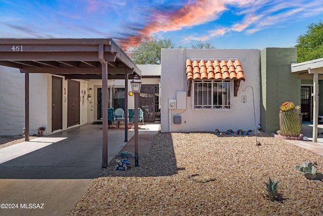 back house at dusk featuring a carport