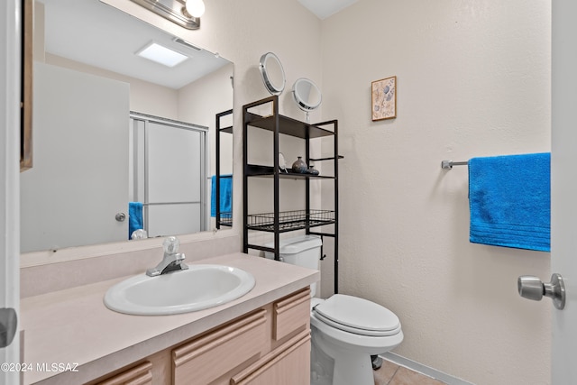 bathroom featuring tile patterned floors, toilet, a shower with door, and vanity