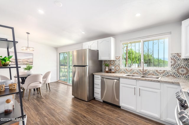 kitchen with white cabinets, appliances with stainless steel finishes, light stone countertops, sink, and dark wood-type flooring