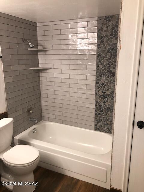 bathroom featuring tiled shower / bath combo, toilet, and hardwood / wood-style floors