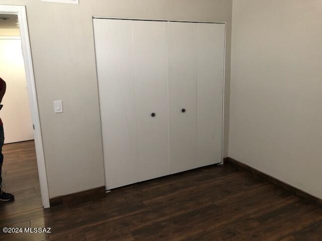 unfurnished bedroom featuring a closet and dark hardwood / wood-style flooring