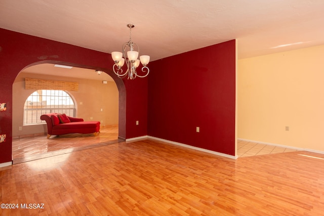 empty room with a notable chandelier and hardwood / wood-style floors