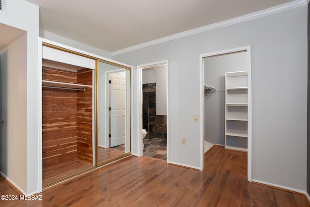 unfurnished bedroom featuring crown molding, hardwood / wood-style flooring, and a walk in closet