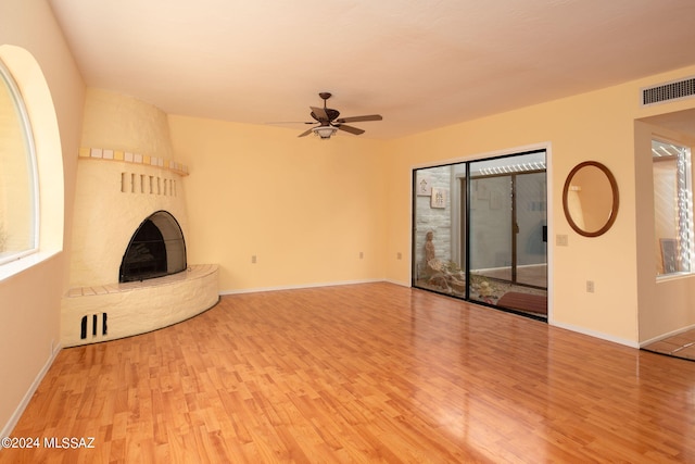 unfurnished living room featuring a large fireplace, ceiling fan, and light hardwood / wood-style flooring