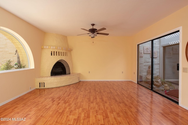 unfurnished living room with a large fireplace, ceiling fan, and light hardwood / wood-style floors