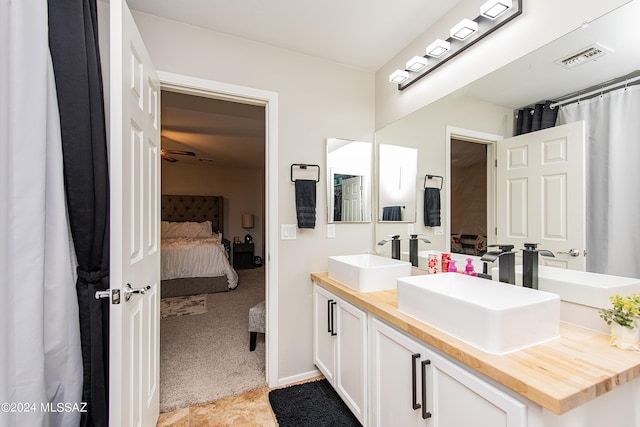 full bathroom with double vanity, connected bathroom, visible vents, and a sink