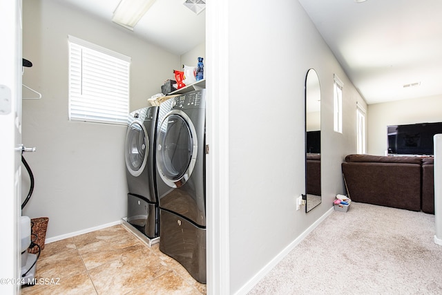 clothes washing area with laundry area, plenty of natural light, visible vents, and washer and dryer