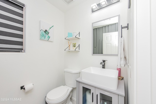 half bath with toilet, visible vents, and vanity