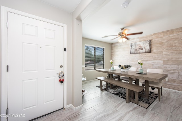 dining room featuring visible vents, wood walls, and a ceiling fan