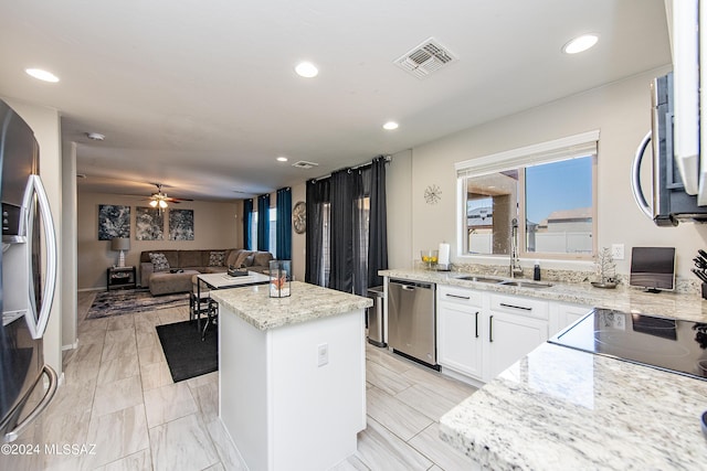 kitchen with a sink, visible vents, white cabinets, appliances with stainless steel finishes, and a center island