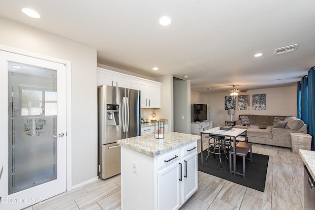 kitchen with recessed lighting, visible vents, white cabinetry, a center island, and stainless steel fridge