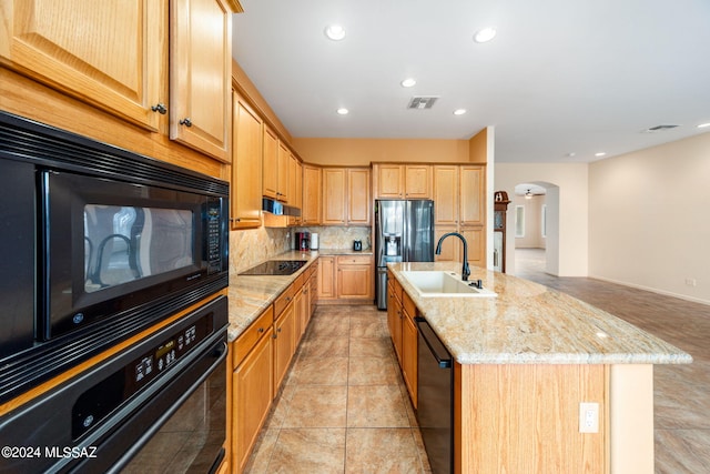 kitchen featuring light stone counters, visible vents, arched walkways, a sink, and black appliances