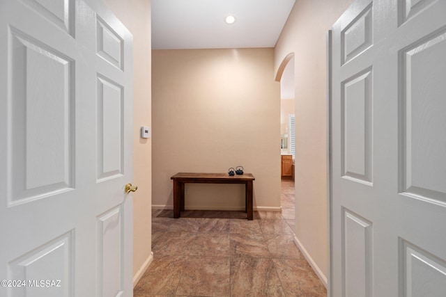 hallway with baseboards and arched walkways