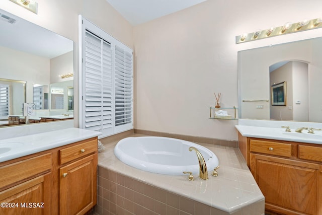 full bathroom featuring a sink, visible vents, a garden tub, and two vanities