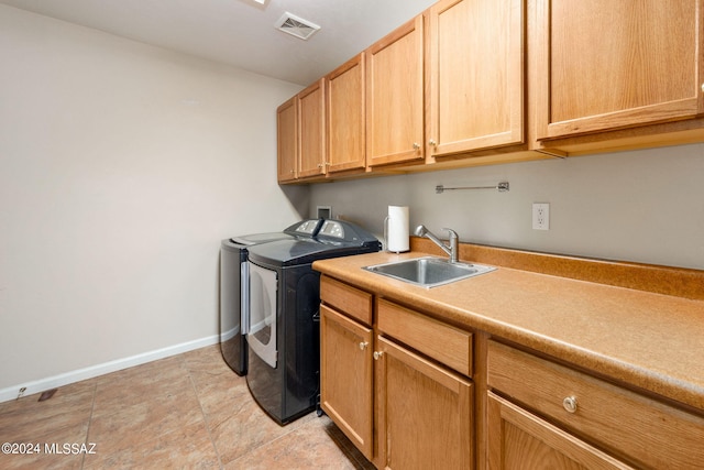 laundry room with baseboards, visible vents, washing machine and clothes dryer, cabinet space, and a sink