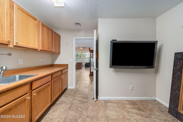 kitchen with light countertops, baseboards, visible vents, and a sink