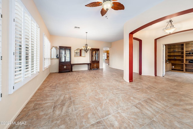 unfurnished living room featuring visible vents, baseboards, and ceiling fan with notable chandelier