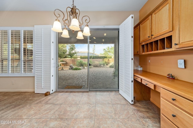 interior space with an inviting chandelier, light tile patterned floors, baseboards, and built in study area