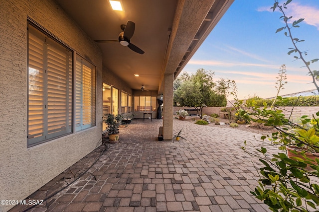 patio terrace at dusk with a ceiling fan and fence