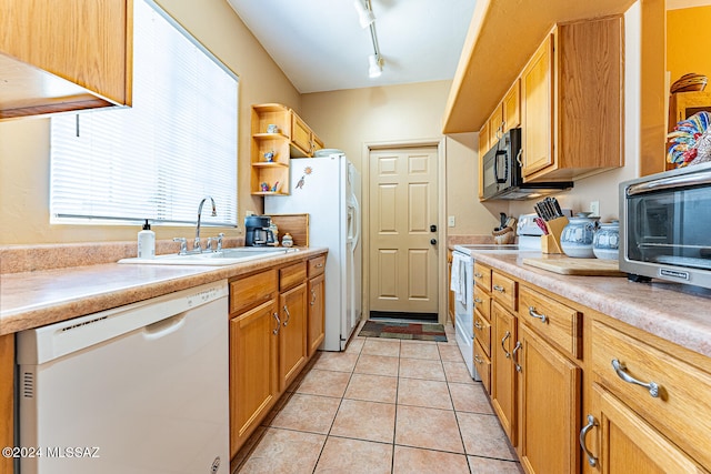 kitchen featuring track lighting, white appliances, light tile patterned floors, and sink