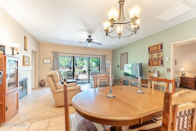 dining space with ceiling fan with notable chandelier, light tile patterned floors, and a tile fireplace