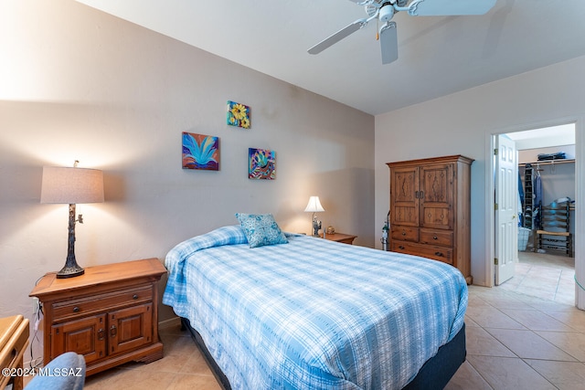 tiled bedroom with a closet, ceiling fan, and a spacious closet