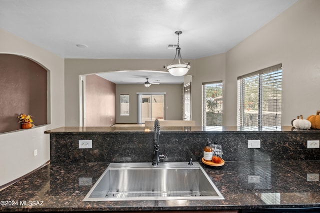 kitchen featuring dishwasher, ceiling fan, sink, and dark stone countertops