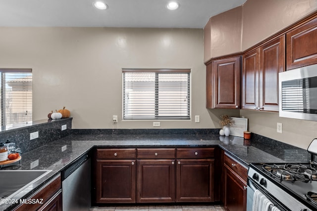 kitchen featuring dark stone countertops, appliances with stainless steel finishes, and dark brown cabinets